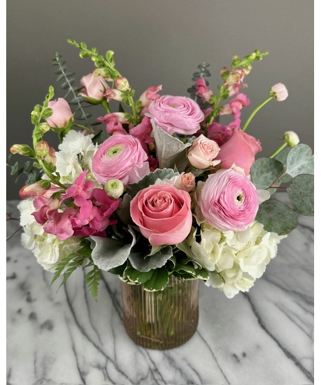 A floral arrangement featuring pink and white blooms, including blush roses, white lilies, and pink hydrangeas. Perfect for elegant and joyful celebrations.