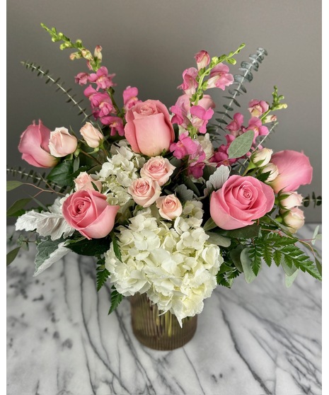 A floral arrangement featuring pink and white blooms, including blush roses, white lilies, and pink hydrangeas. Perfect for elegant and joyful celebrations.