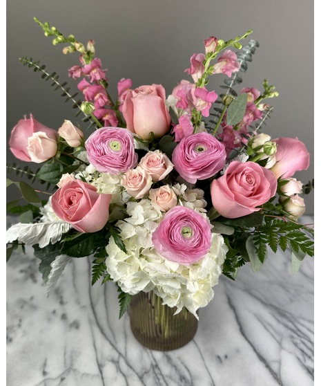 A floral arrangement featuring pink and white blooms, including blush roses, white lilies, and pink hydrangeas. Perfect for elegant and joyful celebrations.