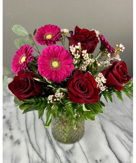 A floral arrangement featuring roses and daisies. 