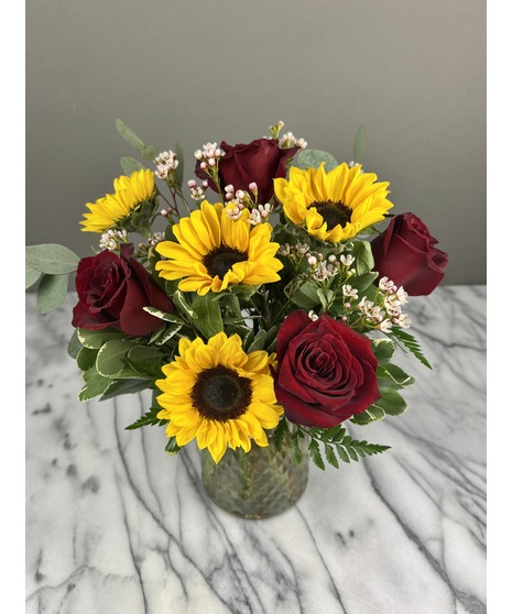 A floral arrangement featuring roses and sunflowers. 