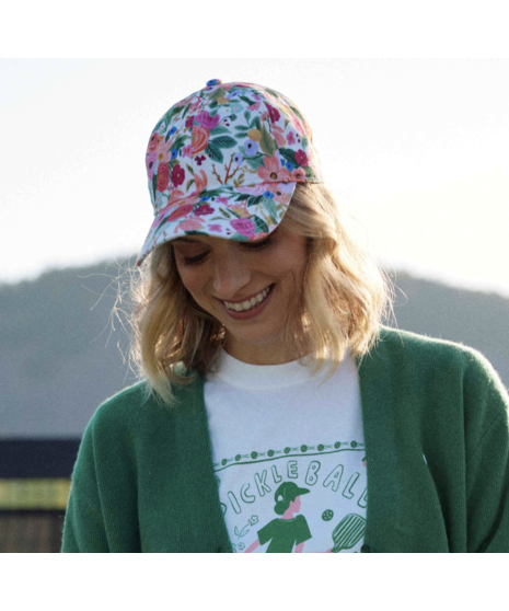 A baseball hat with a colorful floral print featuring pink, orange, and green flowers on a white background.